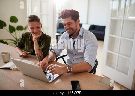 Aufnahme des jungen Paares beisammen sitzen und arbeiten am Laptop. Glücklicher junger Mann und Frau verwenden zu Hause Laptop. Stockfoto