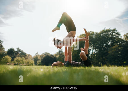 Kaukasische paar Acro Yoga im Park machen. Mann und Frau verschiedene Yogastellungen paarweise im Freien zu tun. Stockfoto