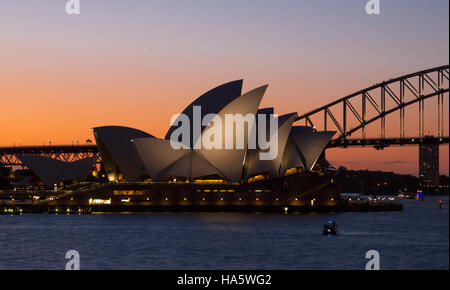 Zwei berühmte Symbole Sydney, Sydney Opera House und Sydney Harbour Bridge beleuchtet in der Abenddämmerung nach einem lebendigen Sonnenuntergang. Stockfoto