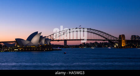 Zwei berühmte Symbole Sydney, Sydney Opera House und Sydney Harbour Bridge beleuchtet in der Abenddämmerung nach einem lebendigen Sonnenuntergang. Stockfoto