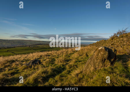 Die Sonne, die Einstellung über ein neblig Aire-Tal in der Nähe von Silsden und Keighley, West Yorkshire, im Winter 2016 Stockfoto