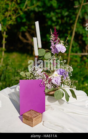 Blumenstrauß und zwei Kerzen auf dem Tisch für eine Trauung im Park Stockfoto