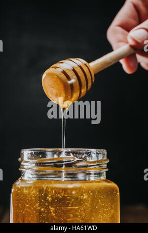 Person DIP Honig-Stick in Stockfoto