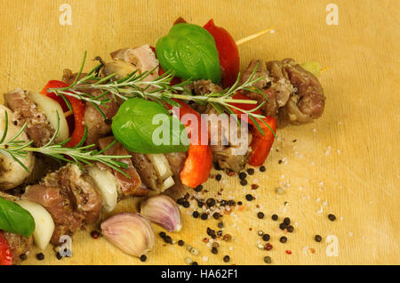 Zwei gebackene Spieße mit Rindfleisch, Champignons, Zwiebeln, Paprika und Speck, garniert mit Zweige Rosmarin und Basilikum und bestreut mit bunten Pfeffer und sal Stockfoto