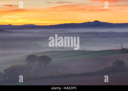 Felder und Nebel in der Nähe von Podere Belvedere bei Sonnenaufgang, San Quirico d ' Orcia, Val d ' Orcia, Toskana, Italien. Stockfoto