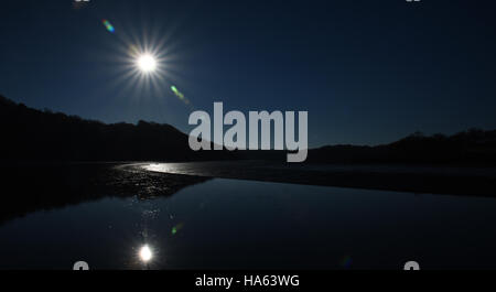 Sternenhimmel Sonne spiegelt sich in ruhigem Wasser bei Ebbe macht eine Silhouette mit tiefblauen Himmel Stockfoto