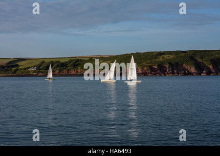 Laser-Jollen racing an einem Sommertag unter einem perfekten blauen Himmel mit Zirruswolken auf ruhigem Wasser in Dale Bucht mit Reflexionen Stockfoto