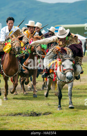 Khampa Reiter, das Tragen von Snow Leopard Pelze, Rasse, ihre Pferde an den Yushu Horse Racing Festival in Qinghai, China. Stockfoto