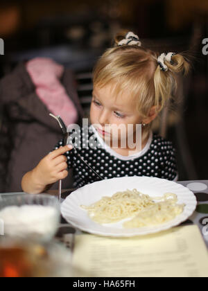 Kleine Mädchen essen Nudeln in einem Café. Stockfoto