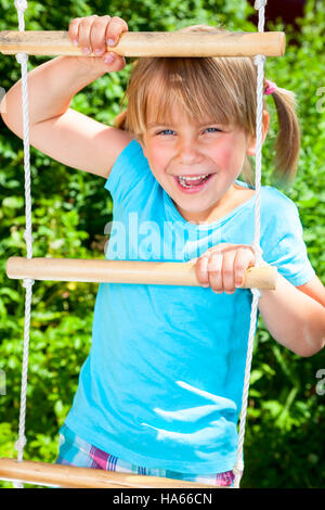 Porträt der niedliche kleine Mädchen spielen auf einer Strickleiter in einem Sommerpark Stockfoto