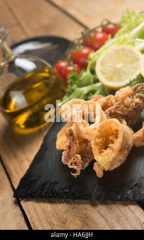 knusprig gebratenen Calamari auf Schiefer Teller serviert Stockfoto