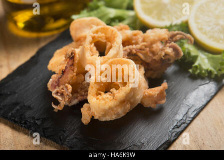 knusprig gebratenen Calamari auf Schiefer Teller serviert Stockfoto