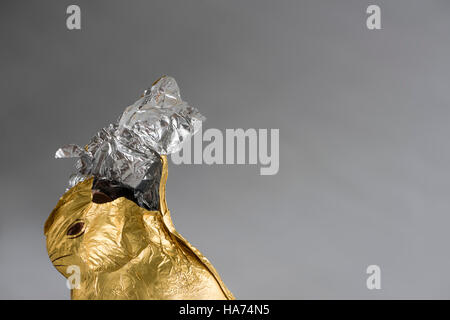 Schoko Osterhase, eingehüllt in glänzenden goldenen und silbernen Aluminium-Folie, knabberte teilweise entfernt, Folie gerissen offen an die Spitze Stockfoto