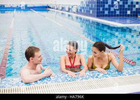 Feiern Sie im Schwimmbad. drei Freunde drinnen tanzen Stockfoto