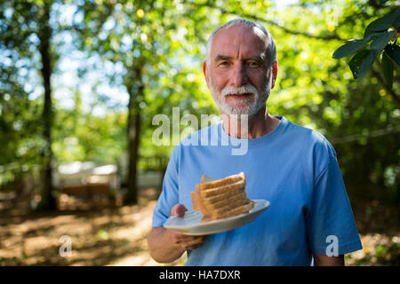 Ältere Mann hält Scheibe Brot in einer Platte Stockfoto