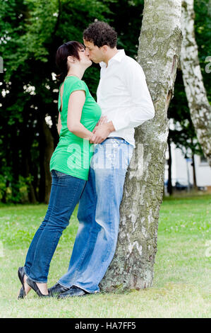 Paar in Liebe an einen Baum gelehnt und küssen Stockfoto