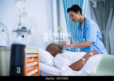 Krankenschwester Anpassung Sauerstoffmaske auf Patienten Mund Stockfoto