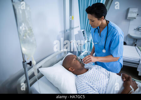 Krankenschwester Anpassung Sauerstoffmaske auf Patienten Mund Stockfoto