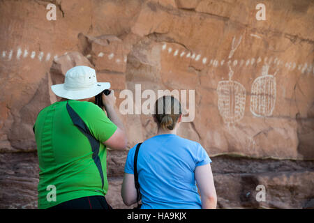 Besucher genießen die antike Felskunst in Peekaboo, einer bedeutenden kulturellen und historischen Stätte im Canyonlands National Park, die die Kunst der indianischen Ureinwohner zeigt. Stockfoto