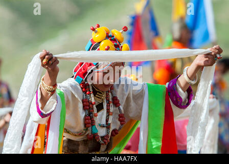 Ein junges Mädchen Khampa bietet einen Seidenschal während einer traditionellen Tanz an der Yushu Horse Racing Festival. Qinghai, China. Stockfoto