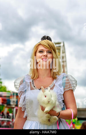 Attraktives weibliches Modell in Alice Kostüm, mit weißen Kaninchen im Wunderland. Stockfoto