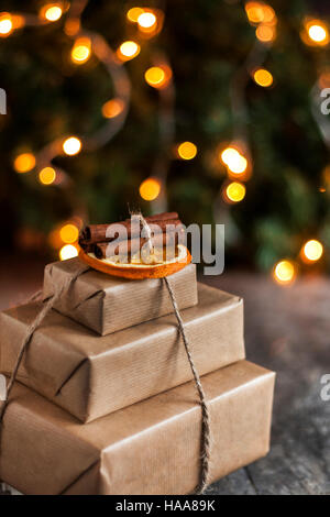 Stapel von verpackten Geschenke auf dem Hintergrund der Weihnachtsbeleuchtung. Stockfoto
