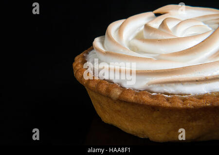 Zitronenkuchen mit Baiser-Törtchen auf schwarzem Hintergrund isoliert Nahaufnahme. Stockfoto