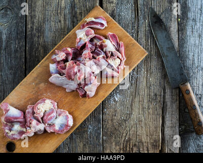 Rohes Hühnchen Keulen auf Schneidebrett auf verwitterten alten Holztisch Stockfoto