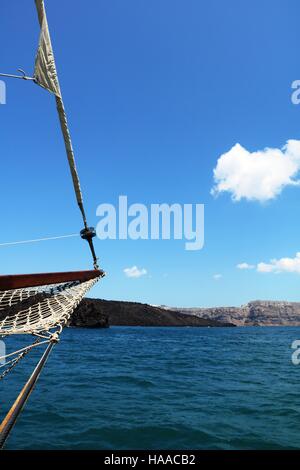 Bild des Mastes eines Bootes driften in die strahlend blauen Wasser gegen den klaren blauen Himmel in Richtung der Caldera in Santorini Stockfoto
