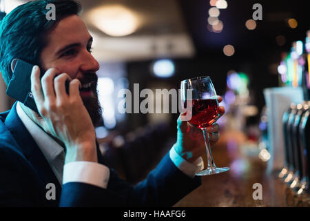 Telefonieren mit Handy während Glas Wein Geschäftsmann Stockfoto