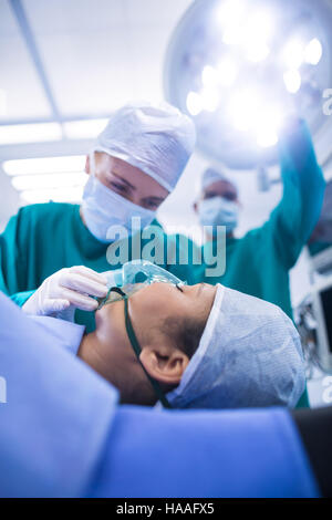 Chirurgen, die Anpassung der Sauerstoffmaske auf Patienten Mund im Betrieb theater Stockfoto