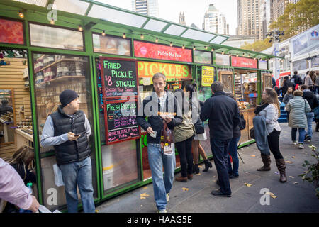 Zahlreiche Besucher auf den Bryant Park Holiday Markt Line-up am Kiosk Pickle mich Pete um sich bei einer Abnahmemenge von gebratenen Gurken, gesehen auf Samstag, 19. November 2016 zu stillen.  (© Richard B. Levine) Stockfoto