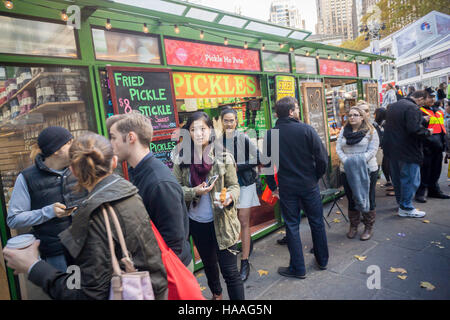 Zahlreiche Besucher auf den Bryant Park Holiday Markt Line-up am Kiosk Pickle mich Pete um sich bei einer Abnahmemenge von gebratenen Gurken, gesehen auf Samstag, 19. November 2016 zu stillen.  (© Richard B. Levine) Stockfoto