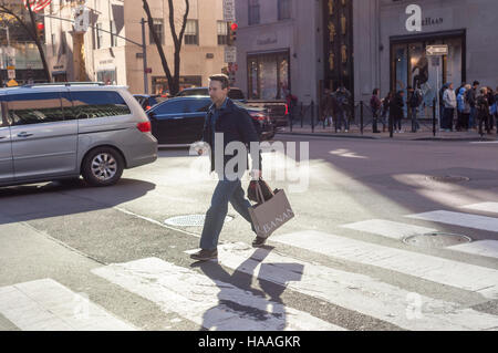 Shopper überquert Fifth Avenue in Midtown Manhattan in New York auf Sonntag, 27. November 2016. Der National Retail Federation berichtete, dass 43,8 % der Verbraucher während der vier-Tage-Wochenende online eingekauft.  (© Richard B. Levine) Stockfoto