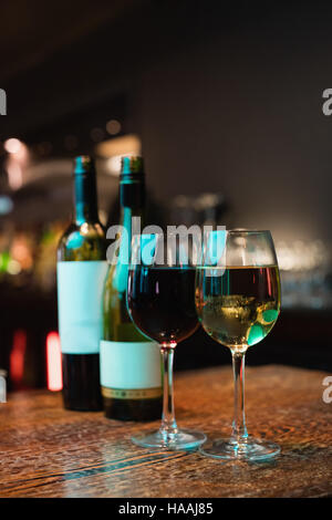 Glas Rotwein und Flaschen auf der Theke Stockfoto