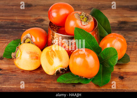 Kaki mit Vintage Kupfer Vase auf altem Holz. Orientalische Stillleben. Stockfoto