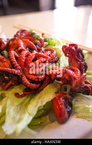 Würzige asiatische Grill kleine Tintenfische auf Salatbett Stockfoto