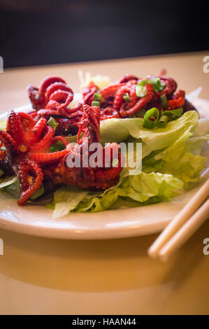 Würzige asiatische Grill kleine Tintenfische auf Salatbett Stockfoto