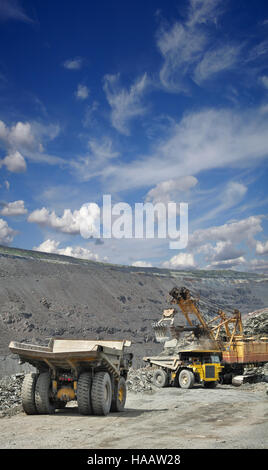 Schwere Muldenkipper sind geladen mit Eisenerz im Tagebau an einem sonnigen Tag im Sommer Stockfoto