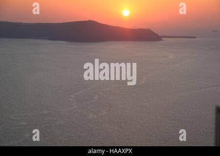 Majestätischen Sonnenuntergang über der Caldera mit einem brillanten Blick auf den klaren orange farbenen Himmel und das offene Meer in Santorini, Griechenland Stockfoto