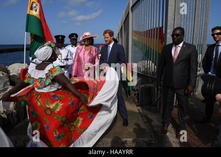 Prinz Harry wird von Gouverneur General Dame Cecile la Grenade (in rosa) begrüßt und Uhren einen Tänzer führen, wie er während der zweiten Etappe seiner karibischen Tour am Kreuzfahrthafen in Grenada, Grenada ankommt. Stockfoto