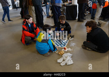 An der Schach-Weltmeisterschaft in der South Street Seaport stattfand, saßen einige Jungs auf dem Boden spielen Schach. 23. November 2016 Stockfoto