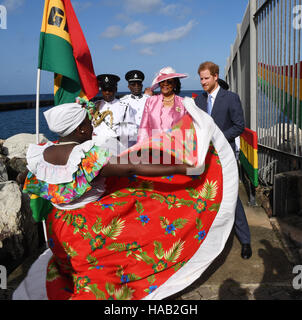 Prinz Harry wird von Gouverneur General Dame Cecile la Grenade (in rosa) begrüßt und Uhren einen Tänzer führen, wie er während der zweiten Etappe seiner karibischen Tour am Kreuzfahrthafen in Grenada, Grenada ankommt. Stockfoto