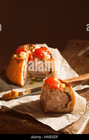 Scheibe von Pork Pie mit Messer geladen mit Senf Stockfoto