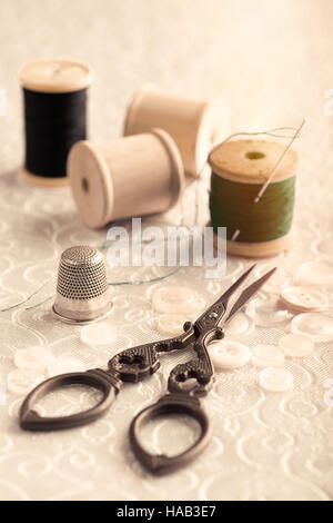 Antike Nähschere und Fingerhut mit Nadeln und Baumwolle Stockfoto
