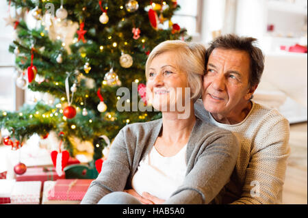 Älteres Paar vor Weihnachten Baum umarmen, hautnah. Stockfoto