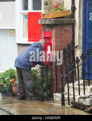 Roya Mail Posta Arbeitskraft Entleerung Dorf Briefkasten im Regen. England. UK Stockfoto