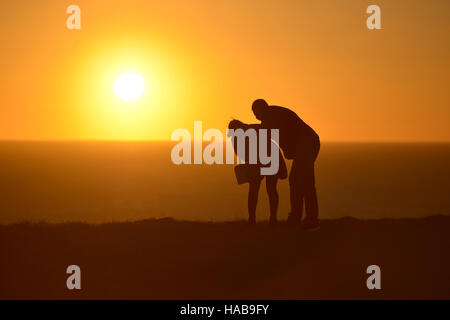 Beachey Kopf, East Sussex. 28. November 2016. Ein paar Peer über den Rand der berühmten Klippen in der Nähe von Beachy Head wie die Sonne setzt an einem sonnigen Tag Beautifuly. Bildnachweis: Peter Cripps / Alamy Live News Stockfoto