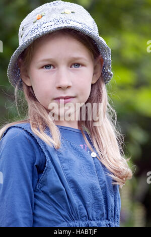 kleines Mädchen im blauen Hut Porträt auf grünen Sommer Hintergrund Stockfoto