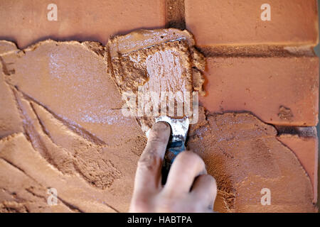 Kelle in der hand Closeup auf rotem Backstein Wand Hintergrund Stockfoto